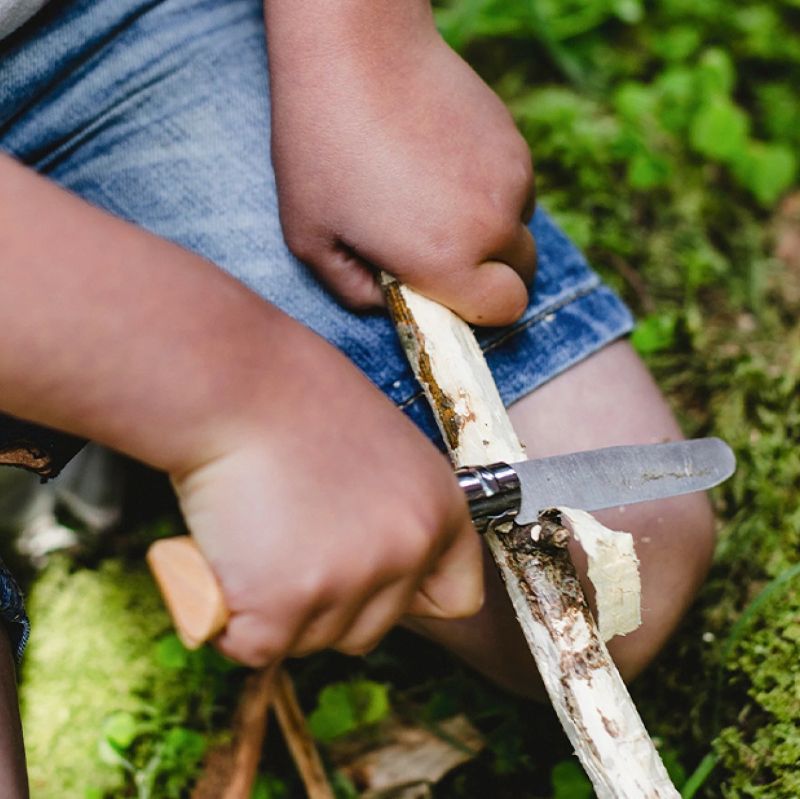 ילד מגלף מקל בטבע - תקריב