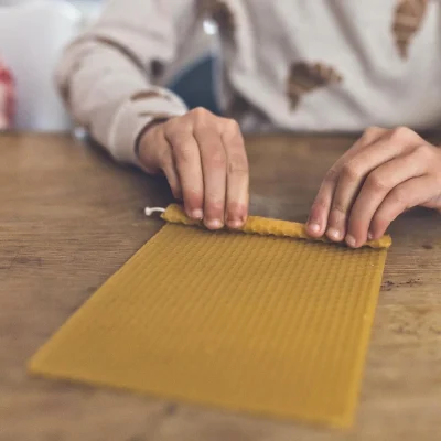 ידיים מגלגלות ניירות שעווה מסביב לפתיל