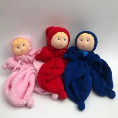 שלוש בובות רכות מבד מגבת בצבעי כחול כהה, אדום, וורוד בהיר.