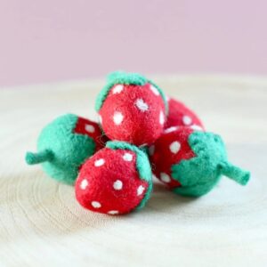 חמישה תותים אדומים עם נקודות לבנות ועלים ירוקים - עשויים לבד. מונחים על משטח עץ