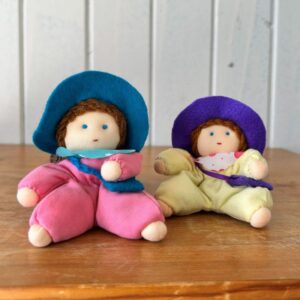 שני גמדונים יושבים על מדף עץ - אחד עם חליפה צהובה ואחד עם חליפה ורודה. שניהם עם כובע ותיק כחול.