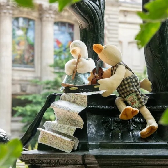 שתי בובות של ברווזים יושבים ברחוב וקוראים במפה